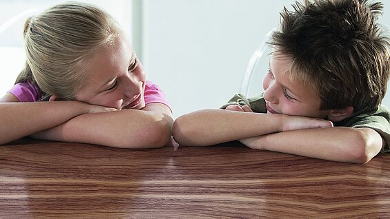 Auch Öle sind mischbar Zwei Kinder welche auf ihren verschränkten Armen liegen und sich anlächeln